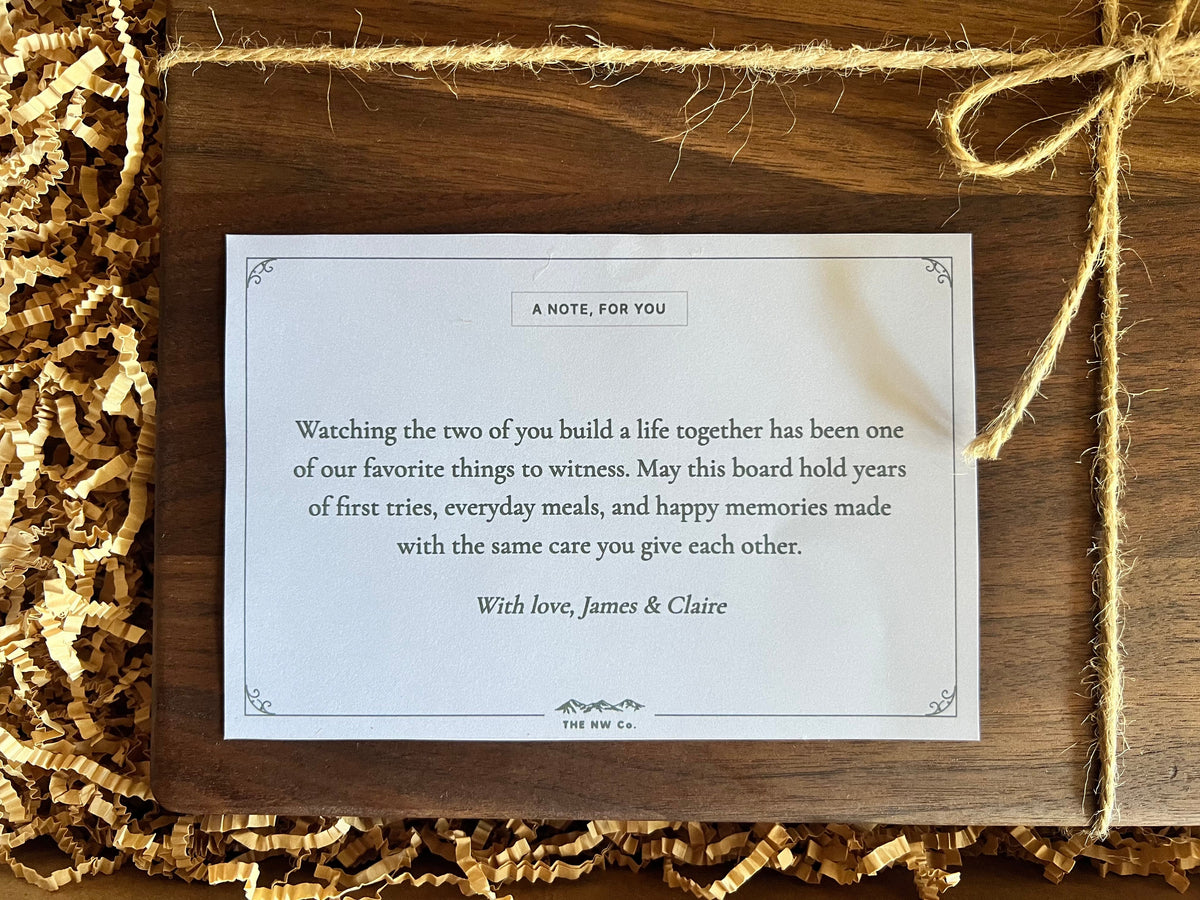 Close-up of the printed note card with a custom gift message, tied with twine on an engraved cutting board