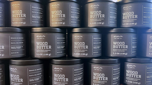 Stacked tins of NW Co. Wood Butter beeswax board conditioner with the new dark label, hand-poured in Albany, Oregon