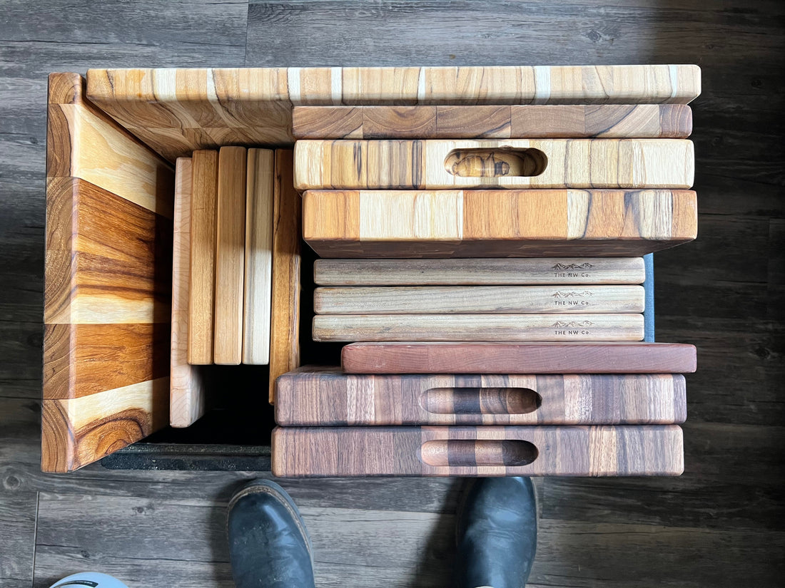 Walnut, maple, and teak cutting boards stacked in the Oregon workshop