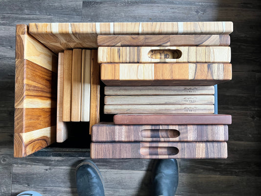 Walnut, maple, and teak cutting boards stacked in the Oregon workshop