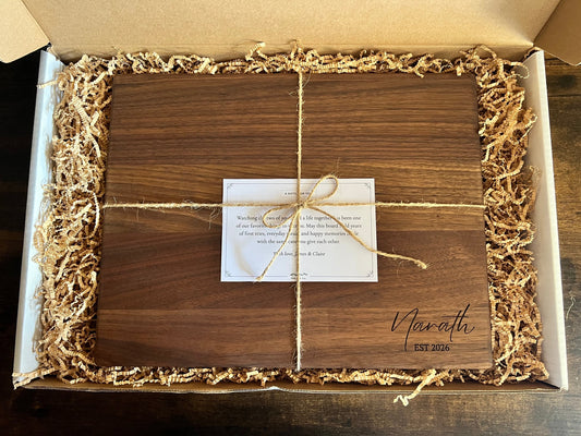 Personalized engraved cutting board packed in a gift box with kraft crinkle paper, twine, and a printed note card