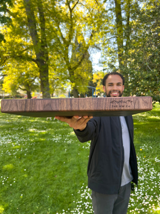 The maker holding a handmade walnut butcher block in Oregon