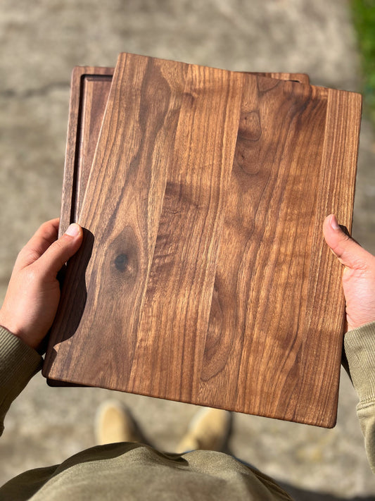 Black walnut cutting board with juice groove beside a hard maple board, ready for engraving