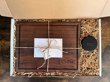 The Charmer gift set: black walnut cutting board engraved LEVINE October 9, 2021 in a gift box with NW Co. Wood Butter tin, kraft crinkle paper, twine and printed note card