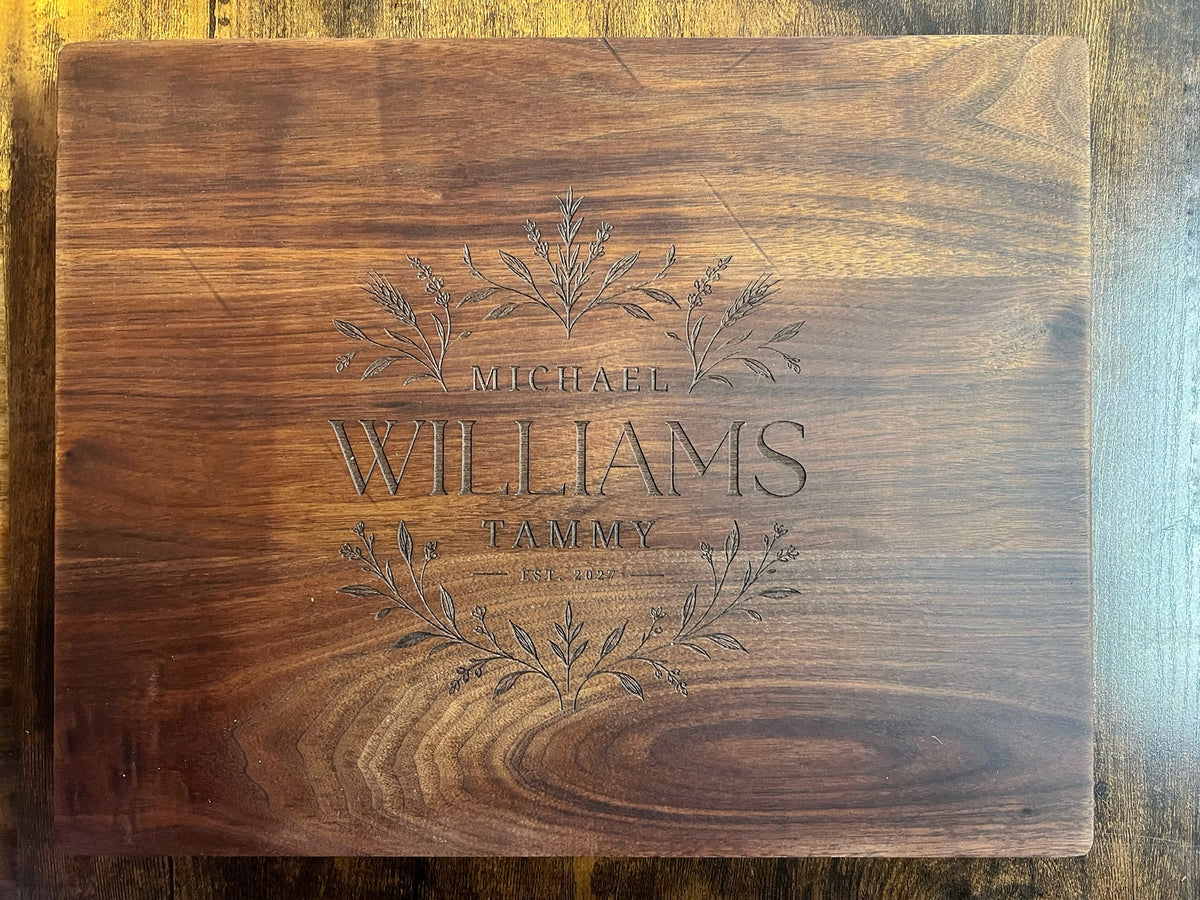 Black walnut cutting board with the Field botanical design engraved across the full face with the names Michael, Tammy and Williams and an established year