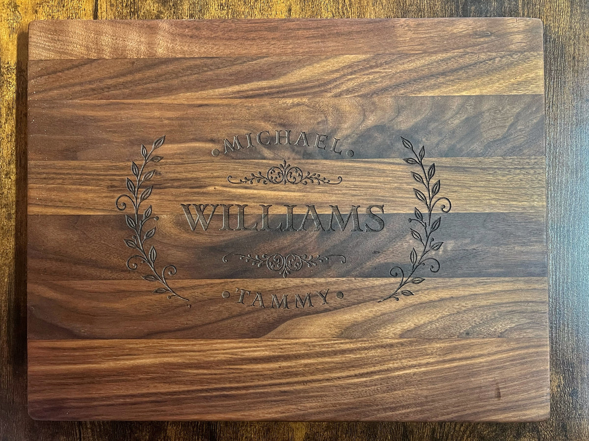 Black walnut cutting board with the Homestead laurel crest engraved across the full face with the names Michael, Tammy and Williams