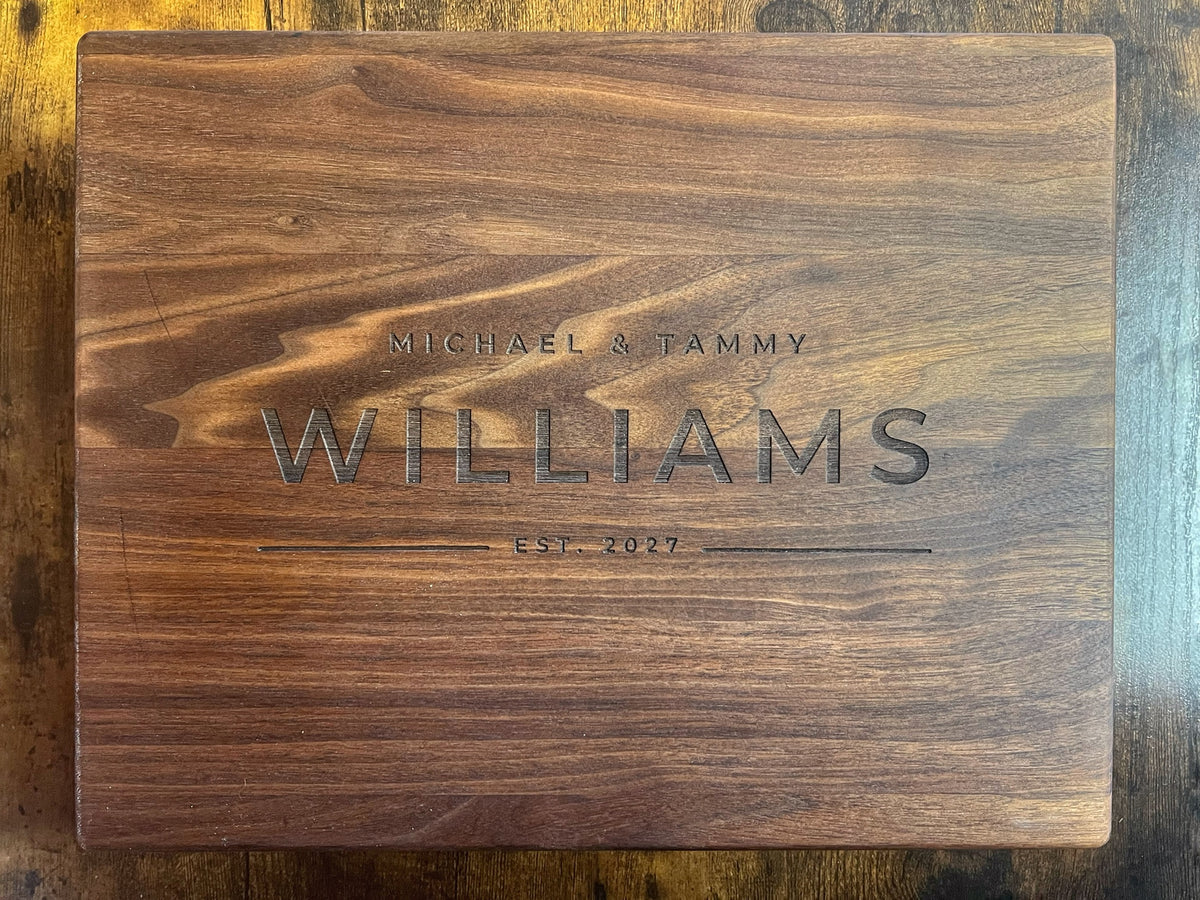 Black walnut cutting board with the Modern design engraved across the full face reading Michael and Tammy, Williams, Est. 2027