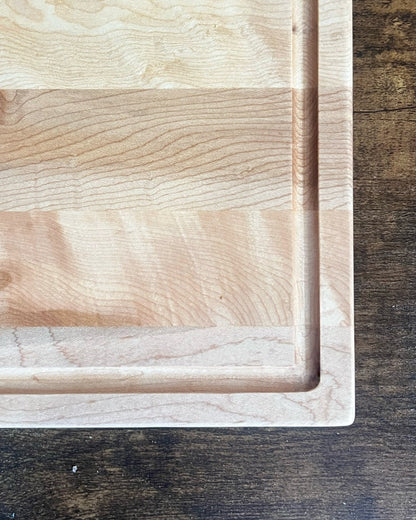 Hard maple cutting board with a juice groove and no engraving, showing the routed channel around the cutting surface
