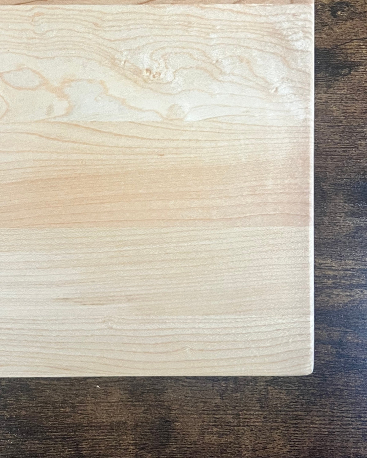 Hard maple cutting board with a smooth finish and no engraving, showing the pale even grain and rounded edge