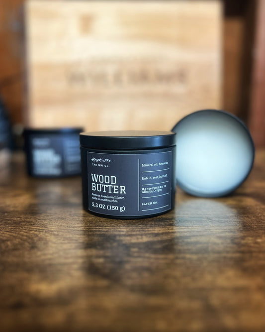 A tin of NW Co. Wood Butter beeswax board conditioner, hand-poured in Albany, Oregon, with the lid off showing the butter inside