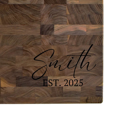 Black walnut end grain butcher block engraved with a family name in script and an EST. date