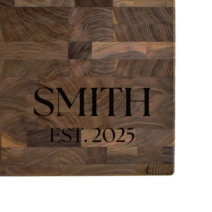 Black walnut end grain butcher block engraved with a family name and EST. date in serif lettering