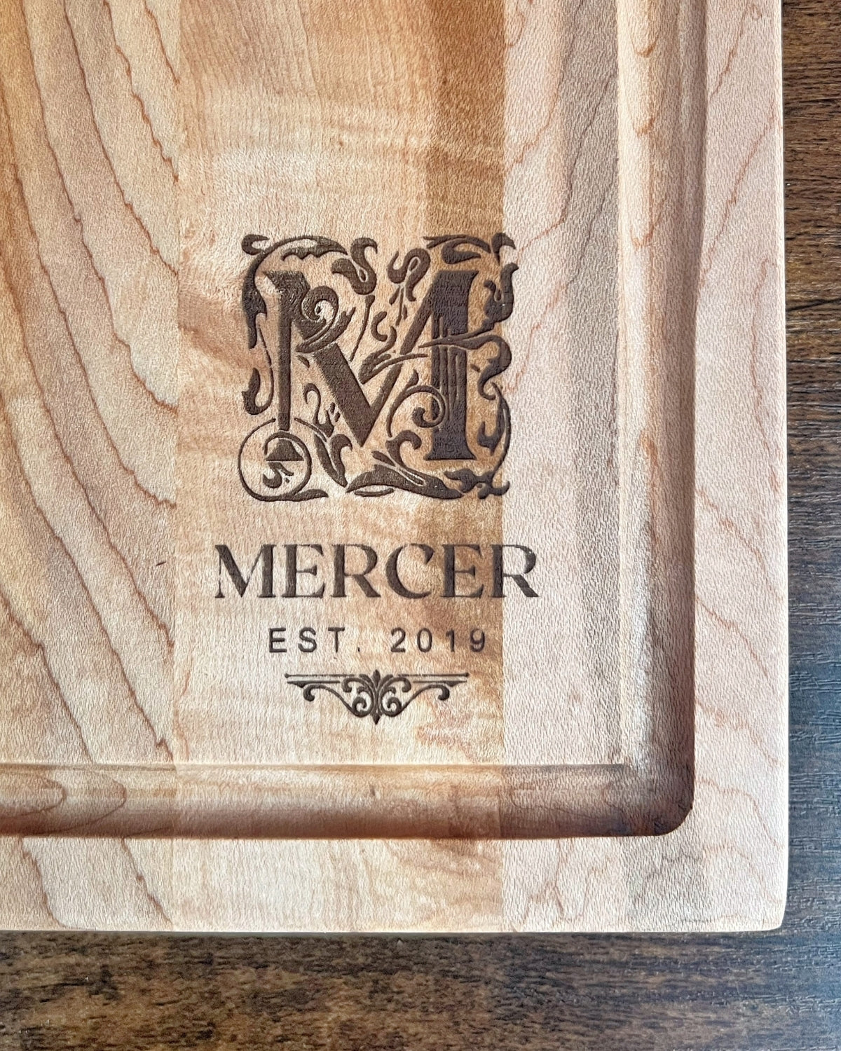 Hard maple cutting board with a juice groove, engraved with an ornate M monogram above the Mercer family name