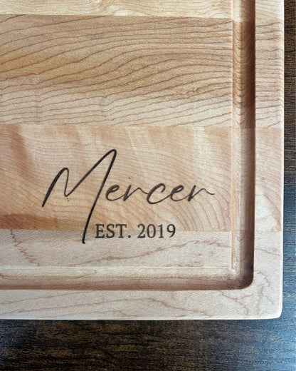 Hard maple cutting board with a juice groove, engraved Mercer EST. 2019 in script lettering