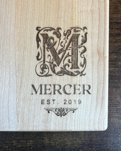 Hard maple cutting board with a smooth finish, engraved with an ornate M monogram above the Mercer family name