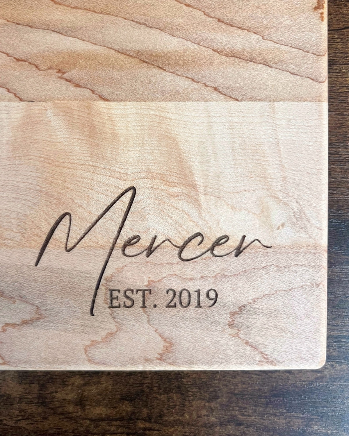 Hard maple cutting board with a smooth finish, engraved Mercer EST. 2019 in script lettering
