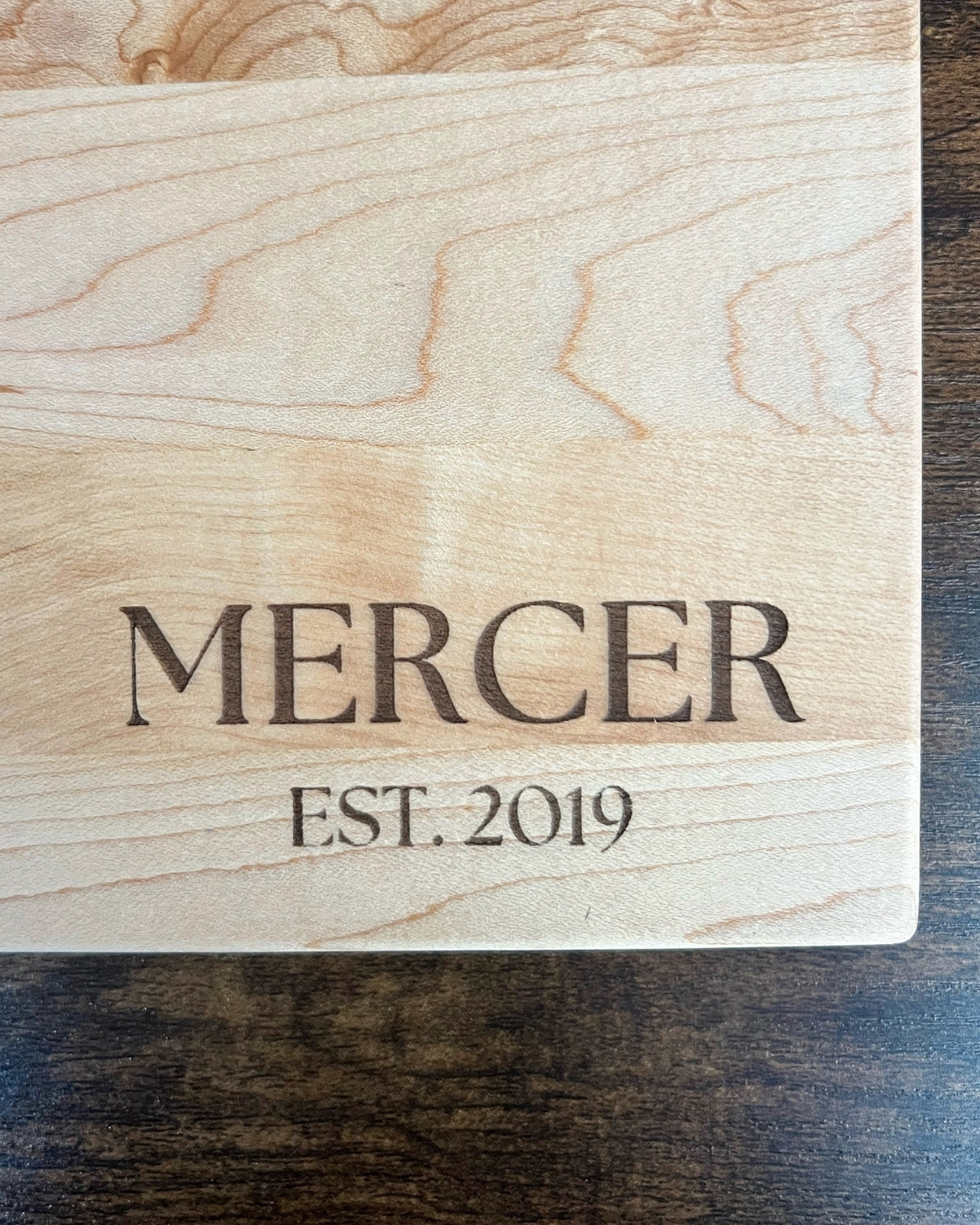 Hard maple cutting board with a smooth finish, engraved MERCER EST. 2019 in serif lettering