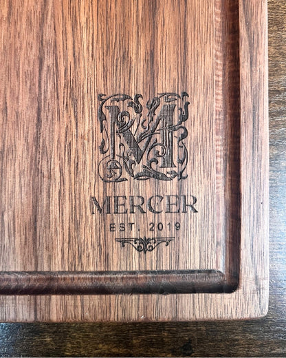 Black walnut cutting board with a juice groove, engraved with an ornate M monogram above the Mercer family name