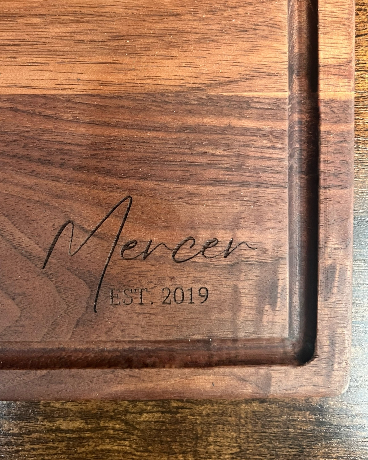 Black walnut cutting board with a juice groove, engraved Mercer EST. 2019 in script lettering
