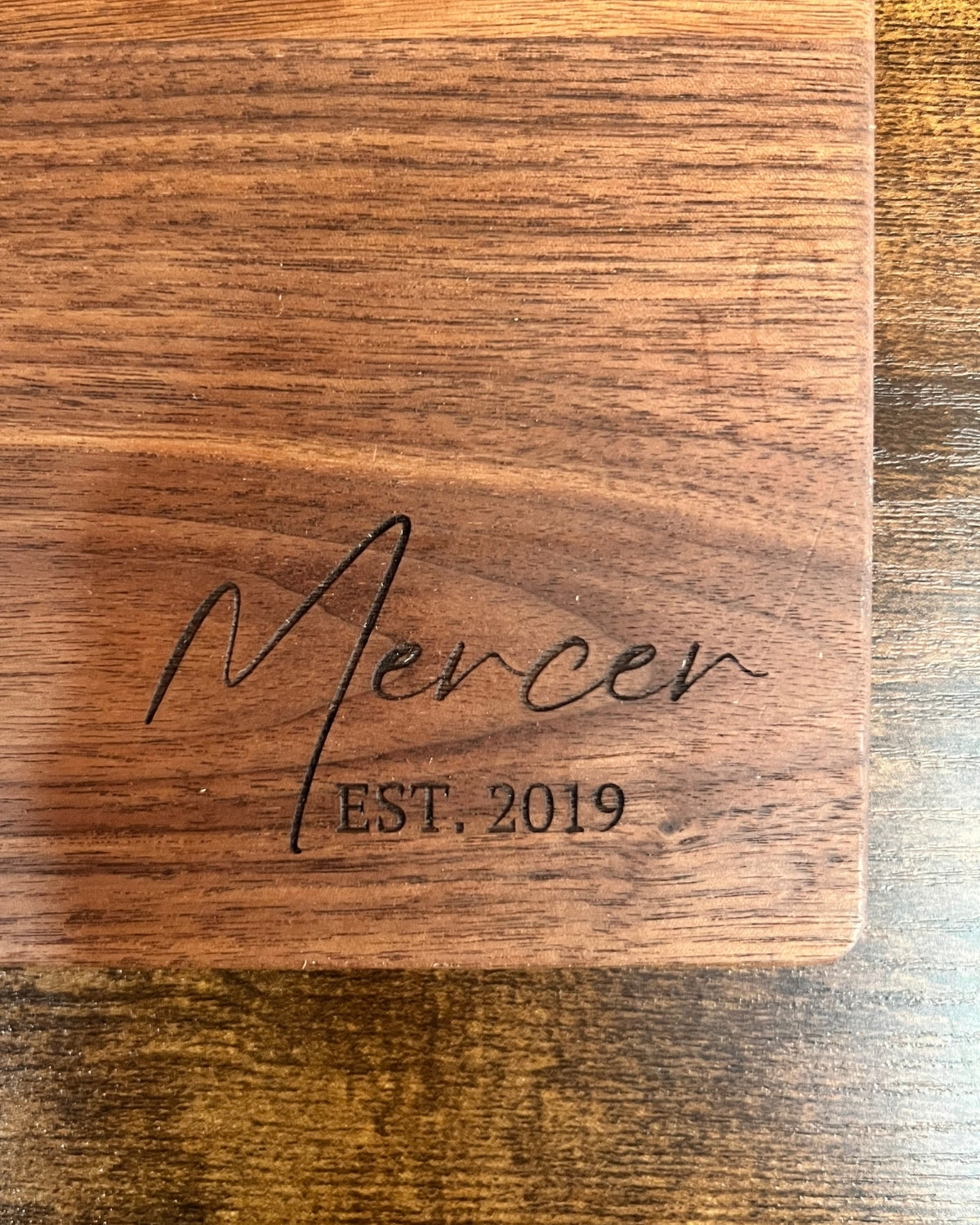Black walnut cutting board with a smooth finish, engraved Mercer EST. 2019 in script lettering