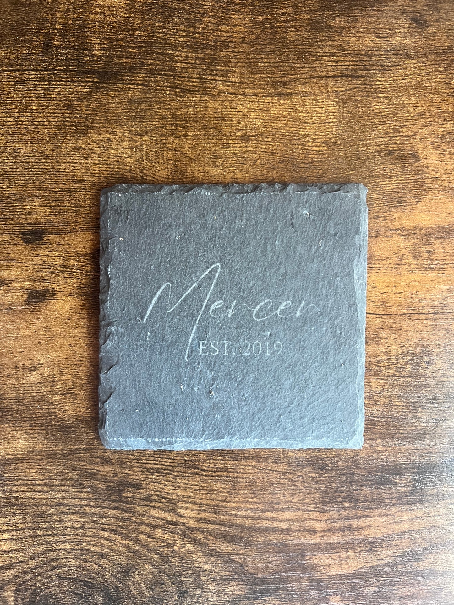 Personalized slate coaster engraved Mercer EST. 2019 in script lettering, shown from above