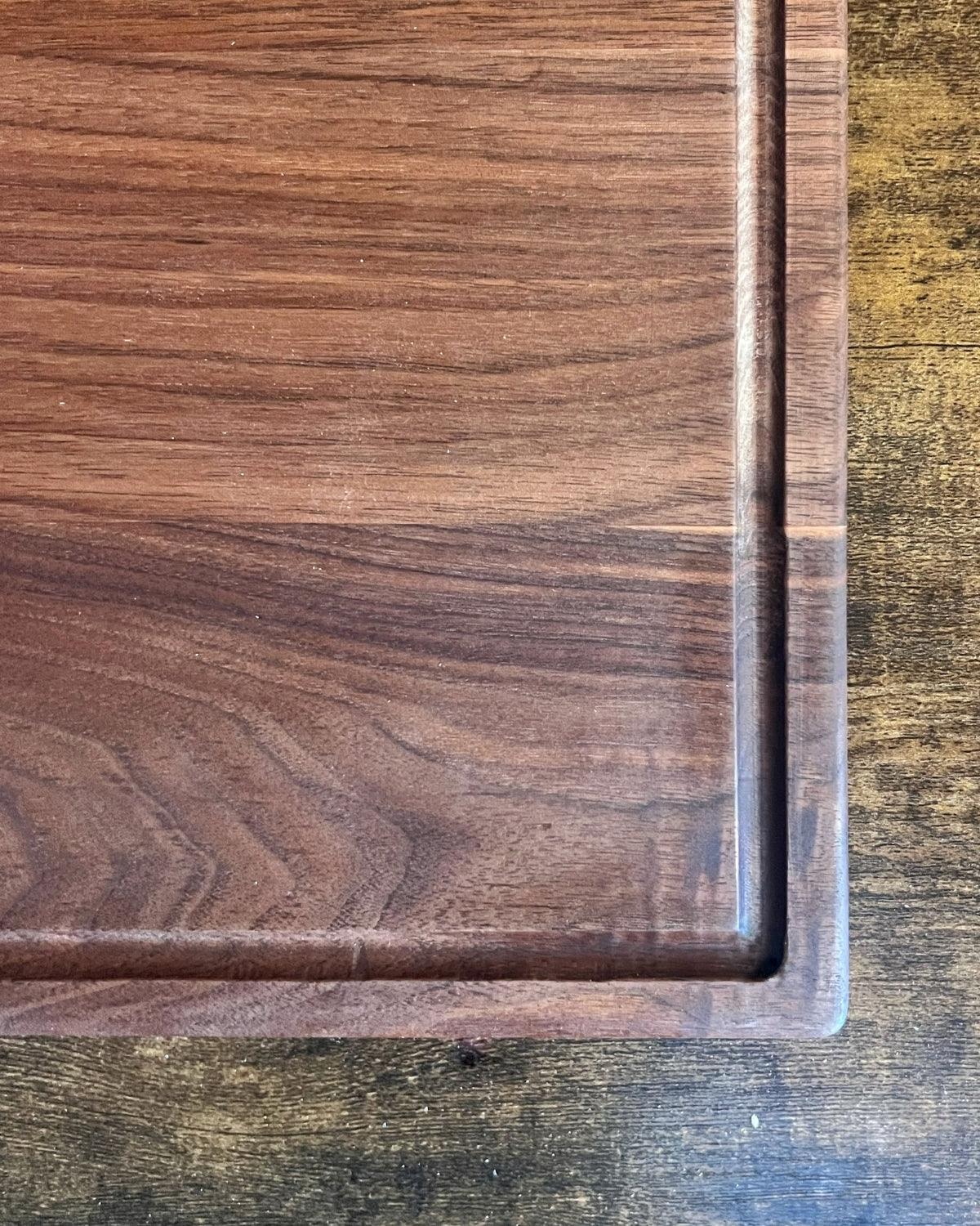 Black walnut cutting board with a juice groove and no engraving, showing the routed channel around the cutting surface